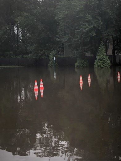 Four orange cones in a very large puddle